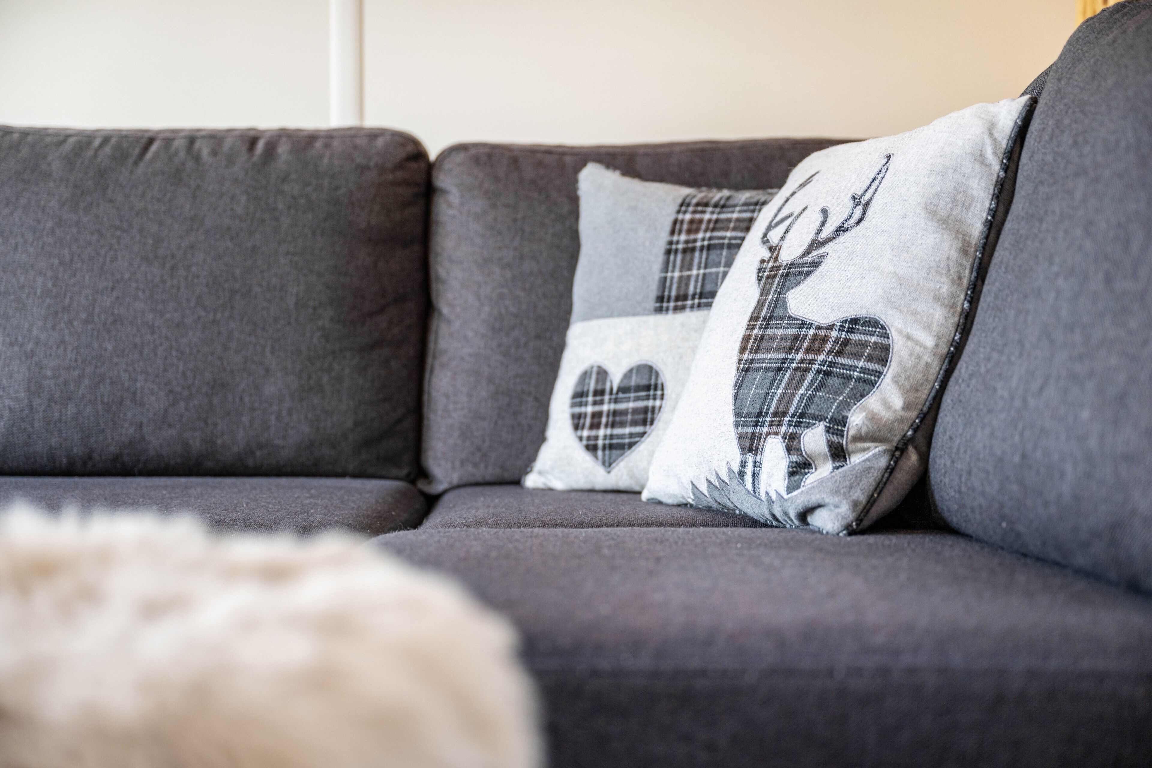 A grey sofa with two decorative pillows featuring a deer and heart design.