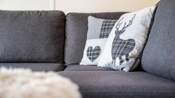 A grey sofa with two decorative pillows featuring a deer and heart design.