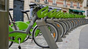 En rad med gröna cyklar parkerade på en kullerstensgata.