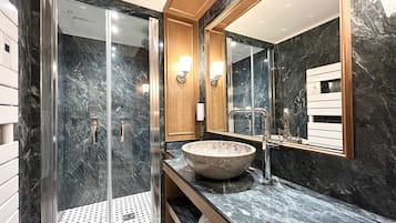 Un baño moderno con ducha envuelta en vidrio, un espejo grande y una encimera de mármol.