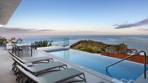 A rooftop infinity pool with a glass edge, lounge chairs, and a view of the ocean. - Superb Top Luxury Villa|GrandView Cristo Rei (Canico)