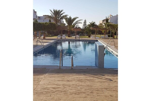 A rectangular swimming pool with clear blue water, surrounded by a tiled deck.