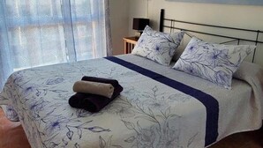 A bedroom with a bed, a ceiling fan, a window with curtains, and a wall-mounted artwork. - Cozy Apartment in Vera, Just Steps from the Beach (Almeria)