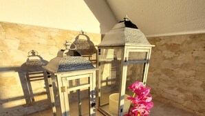 Three glass lanterns with metal tops, one with a pink orchid in a pot. - Cozy Apartment in Vera, Just Steps from the Beach (Almeria)