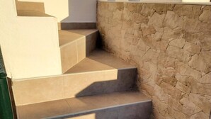 A set of beige-tiled stairs with a stone wall on one side. - Cozy Apartment in Vera, Just Steps from the Beach (Almeria)