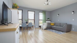 Ein modernes Wohnzimmer mit einer grauen Couch, einem Holztisch und einem Essbereich mit Tisch und Stühlen.