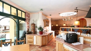 A kitchen with wooden cabinets, a central island, a coffee machine, and a dining area with a table and chairs. - Apartment '12' with Mountain View, Shared Garden and Wi-Fi (Schladming)