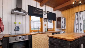 A modern kitchen with wooden cabinets, a built-in oven, and a stone island. - Spacious Apartment in Szczyrk | Garden | Parking (Szczyrk)