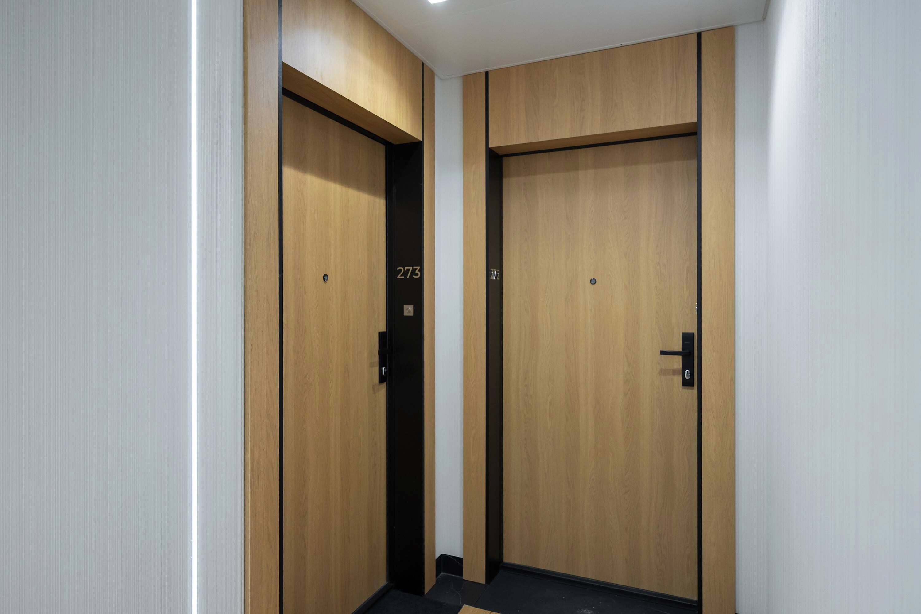 Un couloir avec deux portes en bois, chacune portant un numéro.