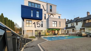 A modern building with a blue and white facade, numbered 15, and a parking area with a disabled parking sign.
