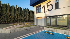 A building with a large '15' sign, a clinic entrance, and a blue tiled area in front.