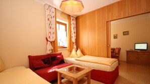 A room with a bed, a sofa, a small table, a TV, and wooden walls. - Apartment '11' with Mountain View, Shared Garden and Wi-Fi (Schladming)