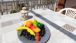 Ett bord med en fruktfat, en lykta och utsikt över havet och palmerna.