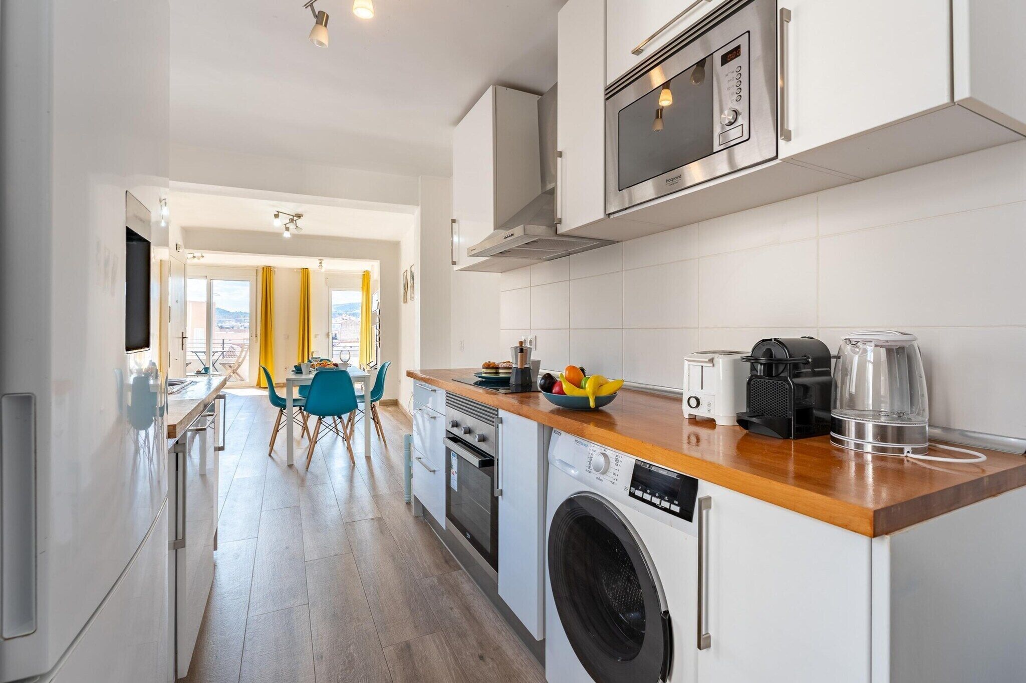 Eine moderne Küche mit Geschirrspüler, Backofen, Mikrowelle und Kaffeemaschine auf der Arbeitsfläche.
