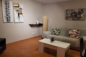 A living room with a grey sofa, a white coffee table, and abstract art on the walls.