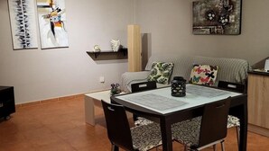 Un área de comedor con una mesa, sillas, un sofá y dos cuadros colgados en la pared.