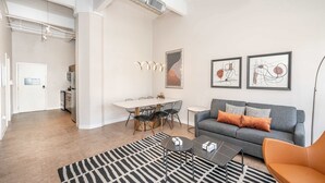 A modern living room with a grey sofa, black and white rug, and abstract art on the wall. - Downtown Cincinnati 2BR Suite | Walk to Stadiums (Cincinnati)