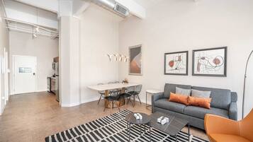 Un salón moderno con un sofá gris, alfombra blanco y negro y arte abstracto en la pared.