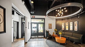 A modern lobby with a reception desk, a sofa, a coffee table, and framed pictures on the wall. - Downtown Cincinnati 2BR Suite | Walk to Stadiums (Cincinnati)