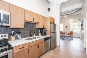 A modern kitchen with wooden cabinets, stainless steel appliances, and a large window providing natural light. - Downtown Cincinnati 2BR, Walk to Reds & Casino (Cincinnati)