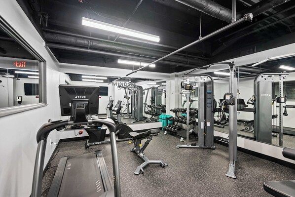 Une salle de sport équipée de tapis de course, d’appareils de musculation et de miroirs.