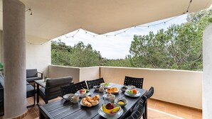 A balcony with a table set for breakfast, outdoor seating, and a view of trees. - Cosy holiday apartment in Elviria, Marbella (Malaga)