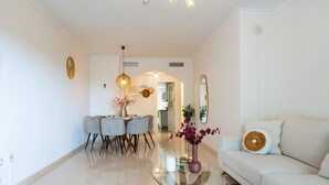 A modern living room with a glass coffee table, a sofa, and a dining area with chairs and a table. - Cosy holiday apartment in Elviria, Marbella (Malaga)