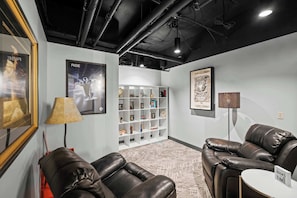 A modern lounge area with leather sofas, a bookshelf, and framed artwork on the walls.