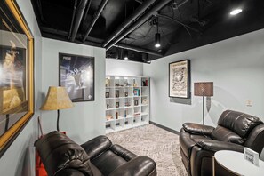 A modern lounge area with leather sofas, a bookshelf, and framed artwork on the walls.