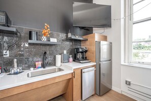 A modern kitchen with a stainless steel refrigerator, a coffee maker, and a microwave.