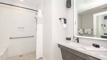 Ein modernes Badezimmer mit Dusche, Waschtisch mit großem Spiegel und Handtuchhalter.