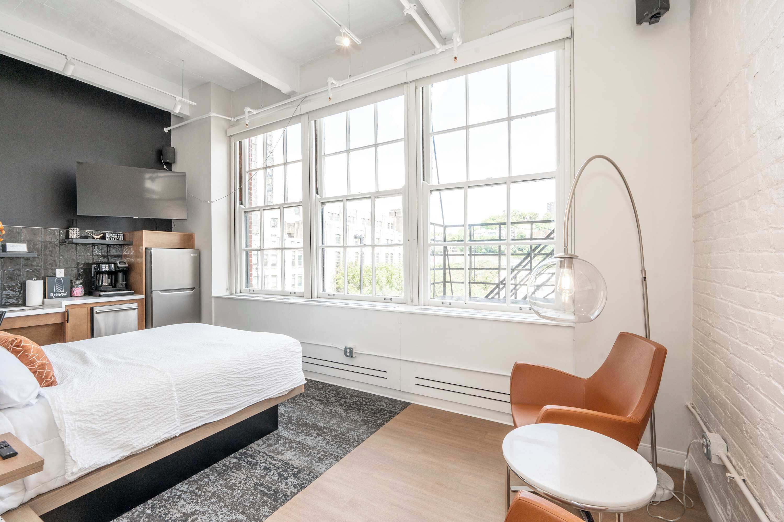 Une chambre d’hôtel moderne avec une grande fenêtre, un lit, un bureau et une chaise.