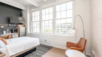 Une chambre d’hôtel moderne avec une grande fenêtre, un lit, un bureau et une chaise.