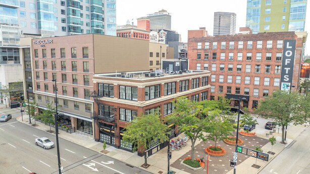 A multi-story hotel with a brick facade, large windows, and a rooftop terrace.