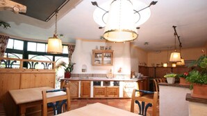 Un'accogliente sala da pranzo con arredi in legno, un'isola centrale e luci a sospensione.