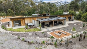 A modern house with a covered patio, a fire pit, and a landscaped garden.