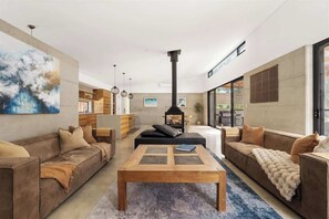 A modern living room with a fireplace, sofas, a coffee table, and artwork on the walls.