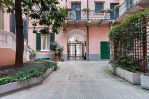 A courtyard with a tiled floor, a central archway, and potted plants. - Blu di Novi Studio | Design District | Salone del Mobile (Milan)