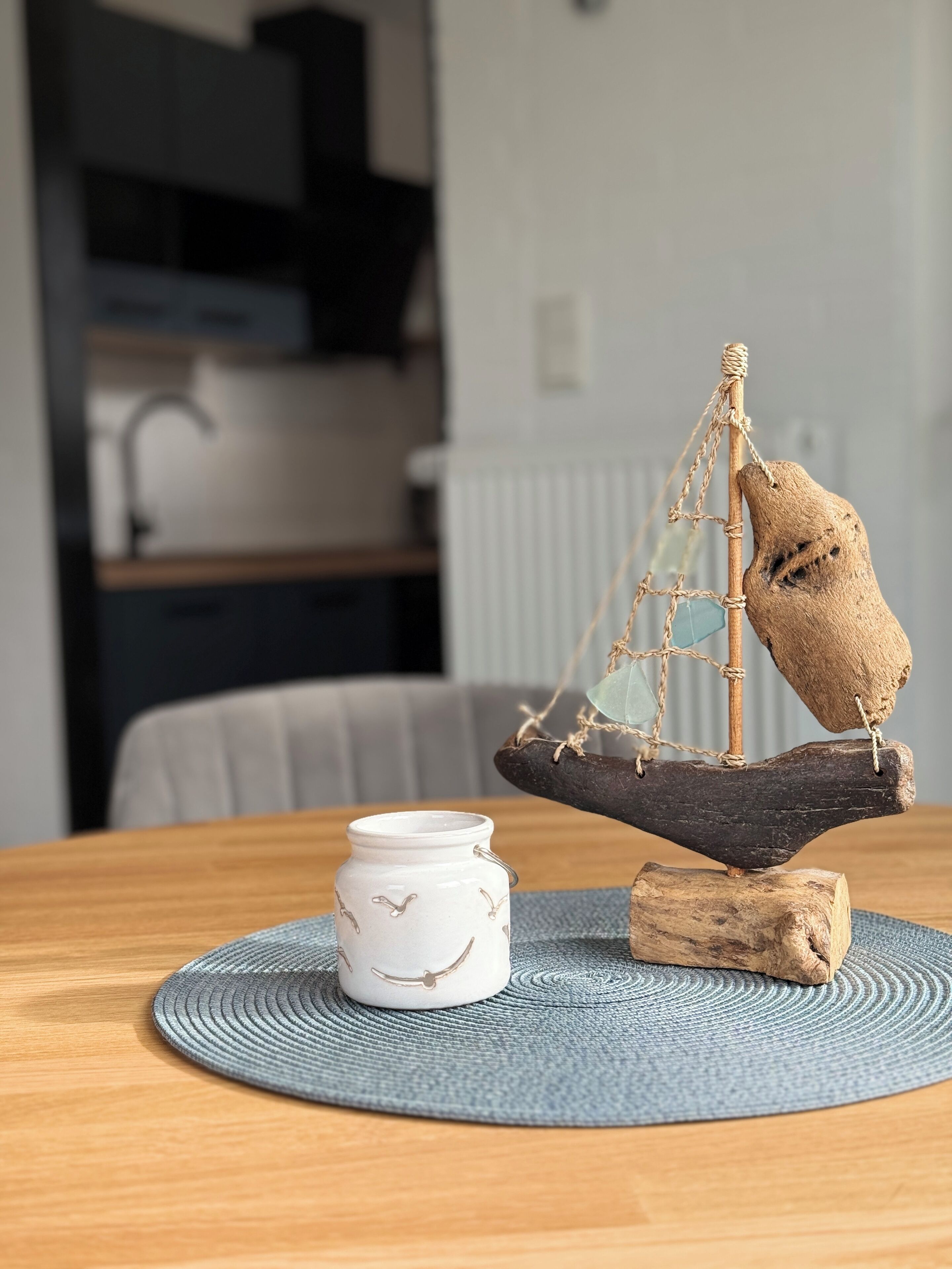 Ein Holztisch mit einem kleinen dekorativen Boot und einem Keramikgefäß.