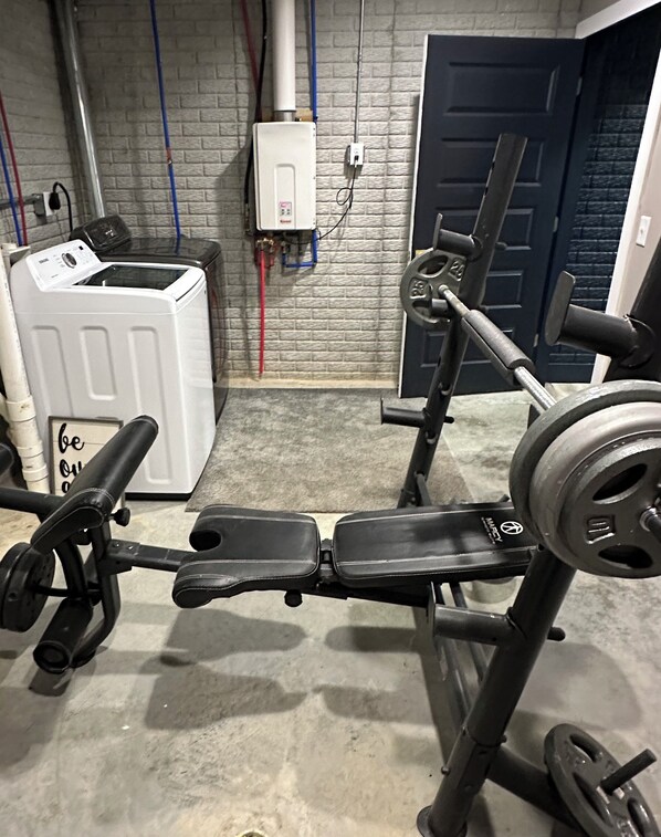 Un gimnasio con equipo de ejercicio, calentador de agua y una puerta al fondo.