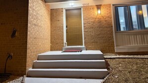 A brick building with a number 9908 on the door, a set of white steps leading to the entrance, and a window to the right. - 


Inviting Bethesda Stay – Clean, Cozy & Convenient (Bethesda)
