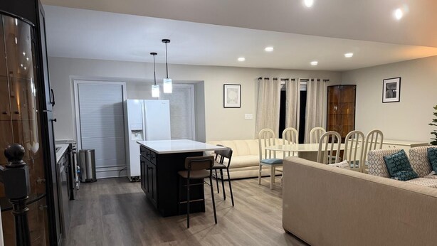 A modern kitchen with a central island, a dining area with a round table and chairs, a sofa, and a refrigerator. - 


Inviting Bethesda Stay – Clean, Cozy & Convenient (Bethesda)