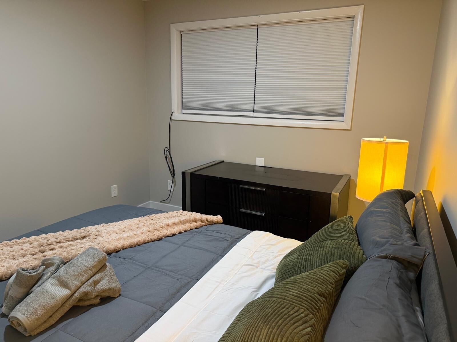 Een slaapkamer met een bed, een bureau en een lamp.