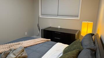 Een slaapkamer met een bed, een bureau en een lamp.