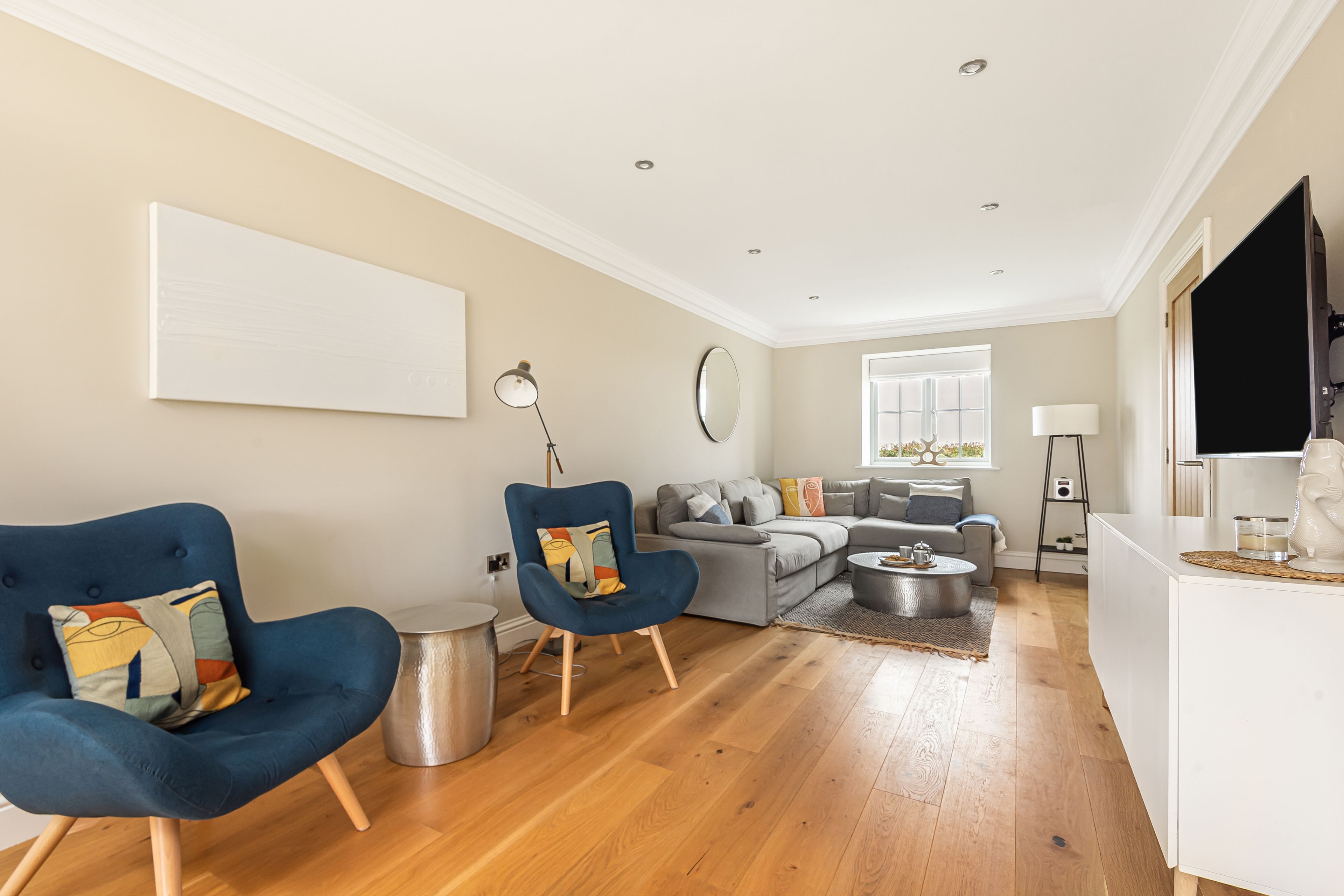 A modern living room with a sofa, two armchairs, a coffee table, and a flat-screen TV.