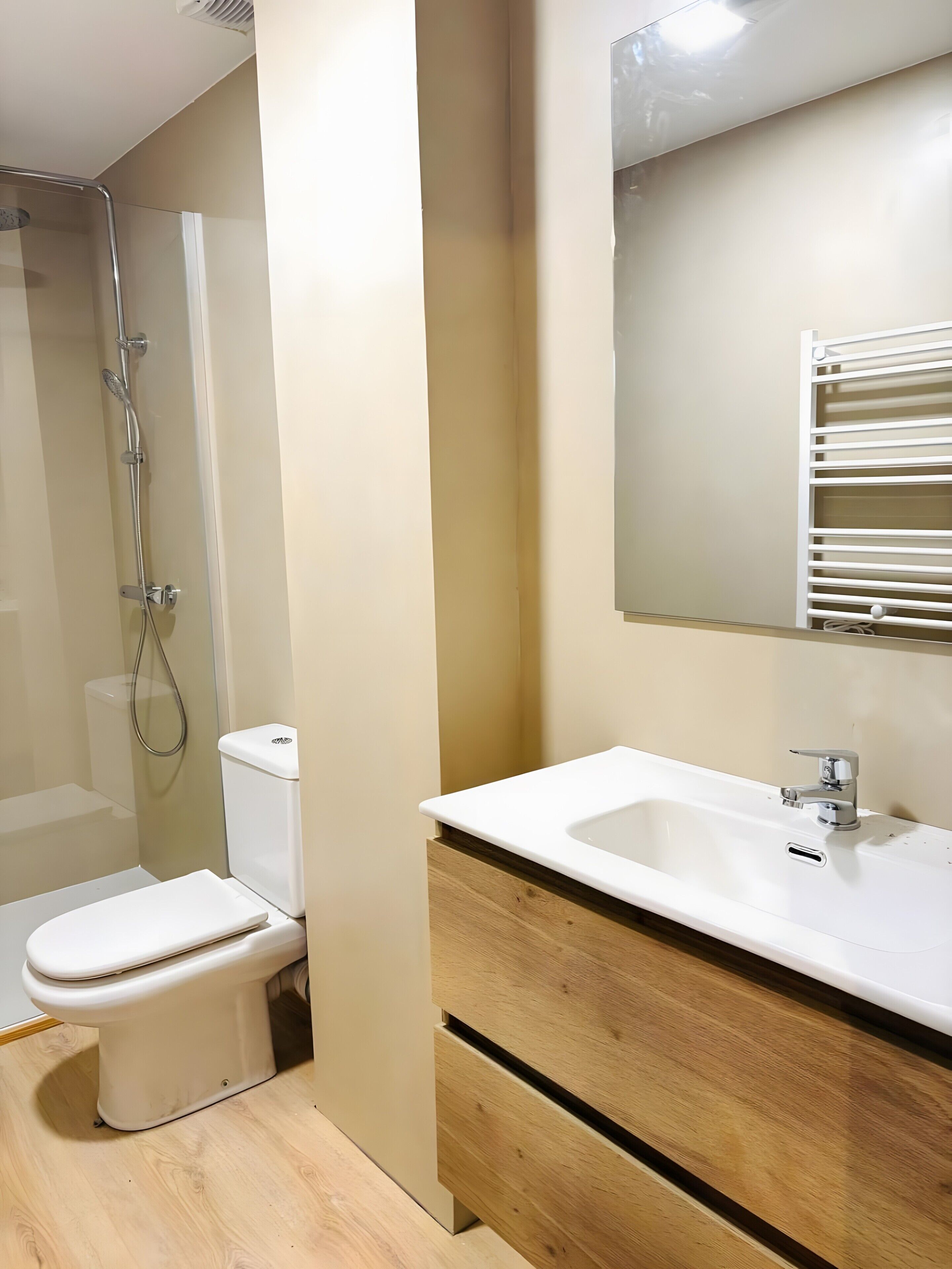 Un baño con inodoro, ducha, lavamanos y espejo.