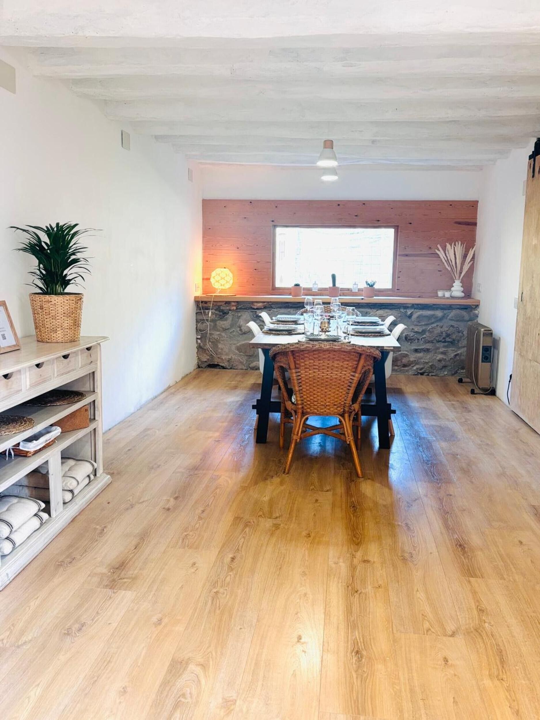 Un comedor con pared de piedra, techo de madera y un ventanal grande.