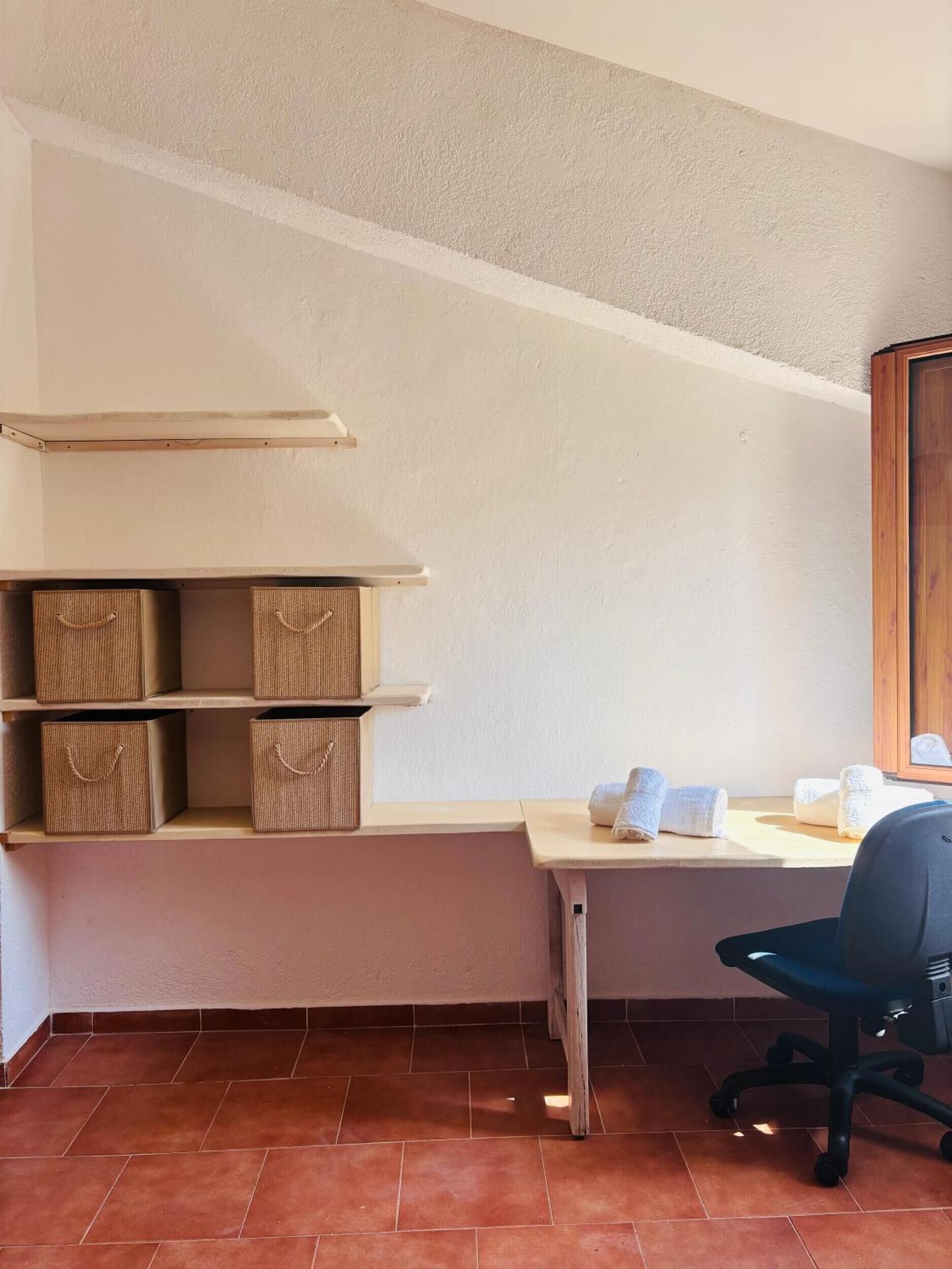 Un bureau d’angle équipé d’un bureau, d’une chaise, d’étagères et de boîtes de rangement.