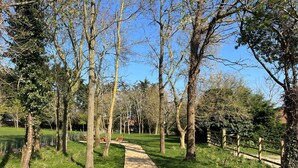 A gravel path winding through a park with trees and a wooden fence. - Sanderling - sleeps 7 guests  in 4 bedrooms (Burnham Market)