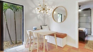 Et moderne værelse med spisebord, stole, bænk, rundt spejl og en unik lampe.